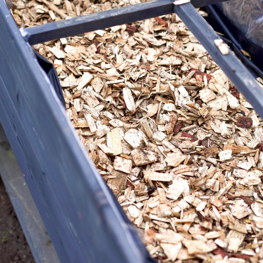 Holzschnitzel in Tischbeet füllen