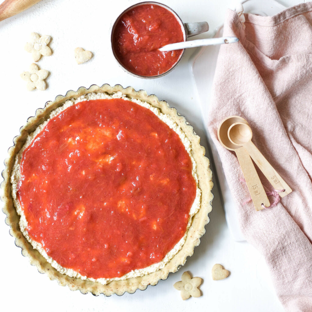 Mandelcreme und Kompott auf Mürbeteigboden streichen