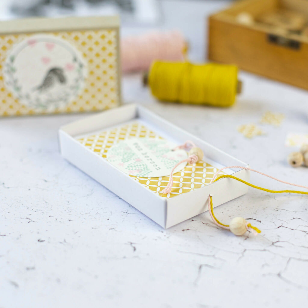 Holzkugel mit Band an Streichholzschachtel binden