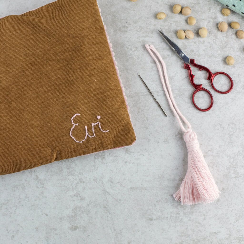 Quaste an Kirschkernkissen annähe