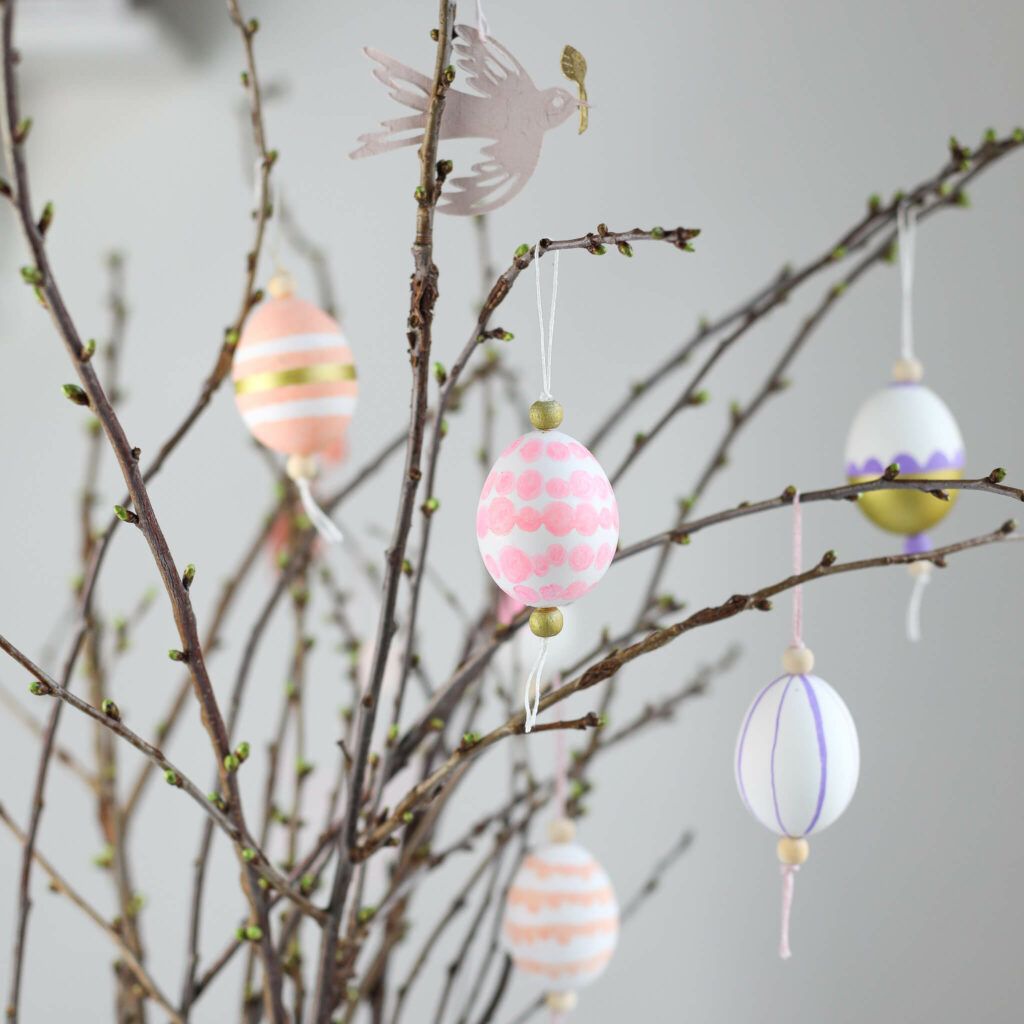Bemalten Ostereier an Kirschblütenzweige hängen