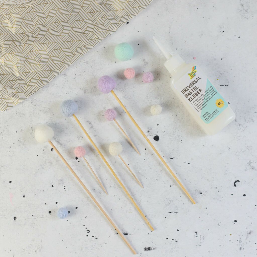 Filzkugeln auf Holzspieße kleben und auf die Torte stecken
