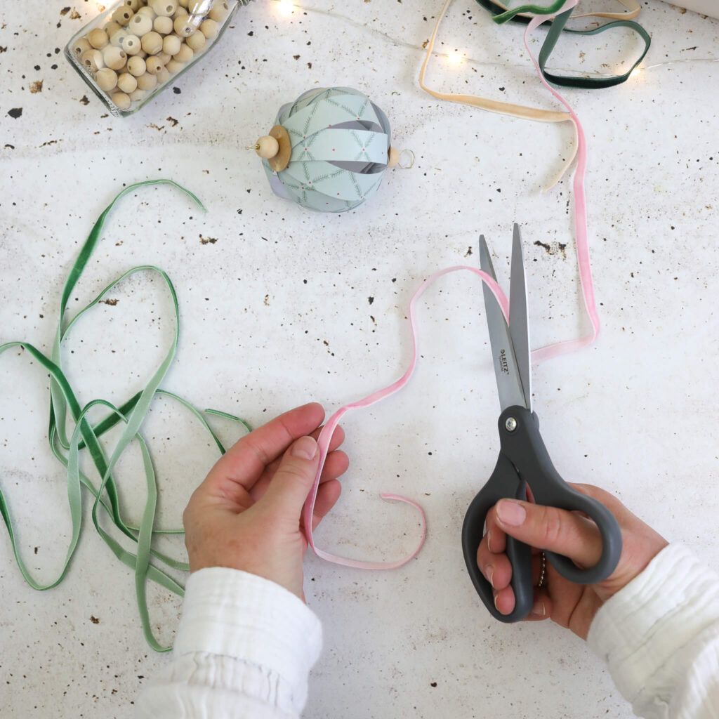 Samtbänder an Weihnachtskugeln aus Papierstreifen anbinden