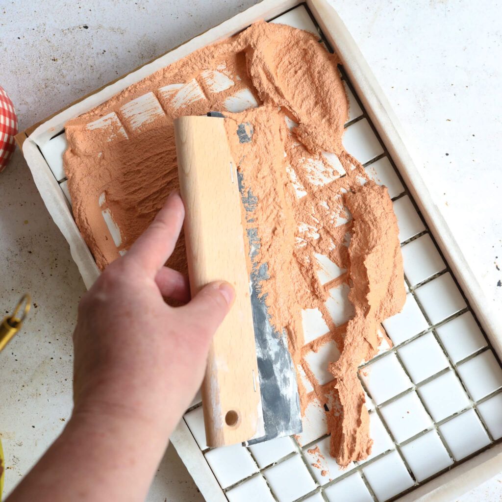 Fugenmasse mit Acrylfarbe mischen und auf die Fliesen auftragen.
